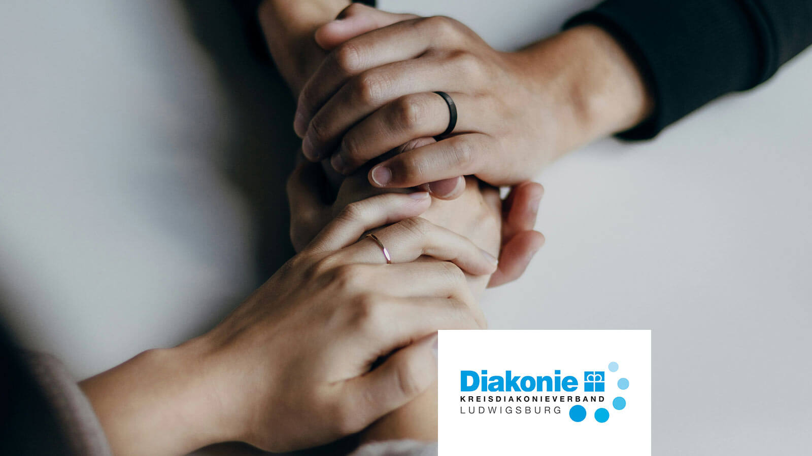 Zwei ineinander verschränkte Hände als Zeichen von Unterstützung und Zusammenhalt, mit Logo des Kreisdiakonieverbands Ludwigsburg