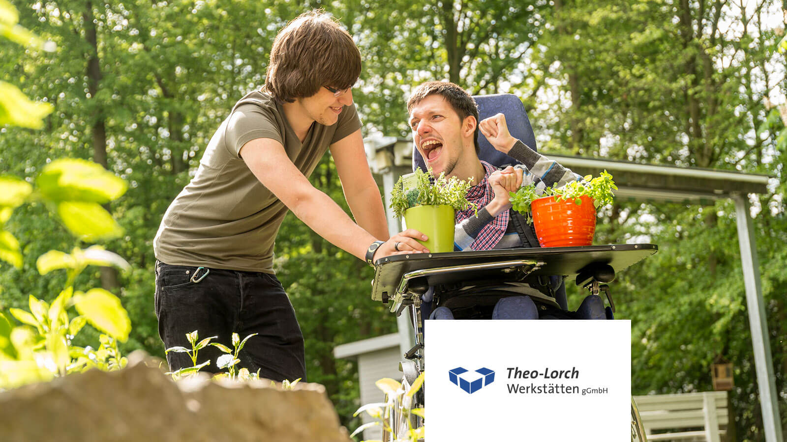 Ein betreuter Mensch im Rollstuhl arbeitet freudig mit Pflanzen im Grünen, begleitet von einer unterstützenden Fachkraft. Inklusive Arbeit, Teilhabe und soziale Förderung in den Theo-Lorch-Werkstätten.