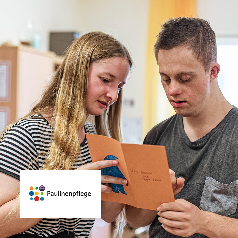 Zwei junge Menschen gestalten gemeinsam eine Karte in der Paulinenpflege.