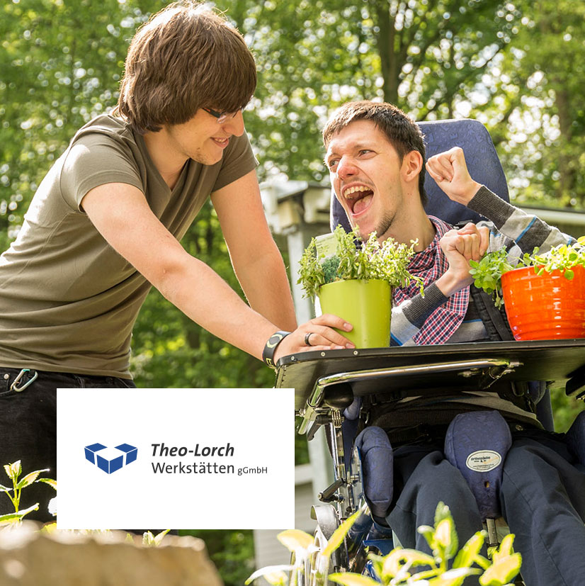 Ein betreuter Mensch im Rollstuhl arbeitet freudig mit Pflanzen im Grünen, begleitet von einer unterstützenden Fachkraft. Bild für inklusive Arbeit, Teilhabe und soziale Förderung in den Theo-Lorch-Werkstätten.