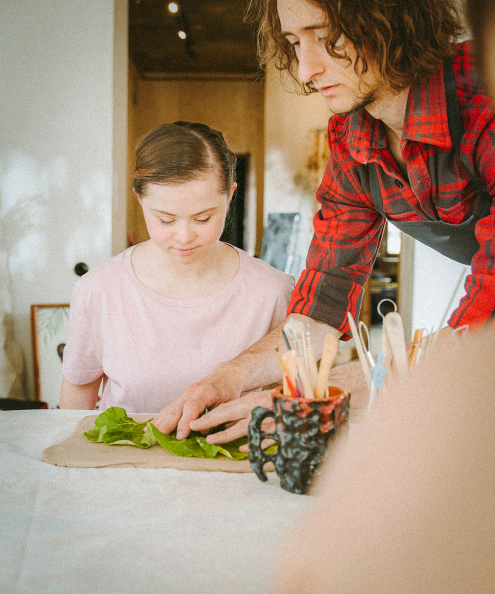 Junges Mädchen mit Down Syndrome und ein junger Mann kochen zusammen.