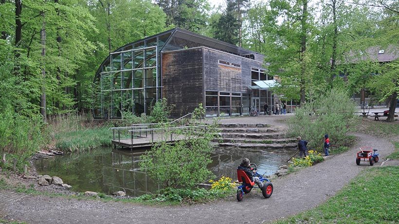 Haus des Waldes Stuttgart, davor mehrere spielende Kinder.