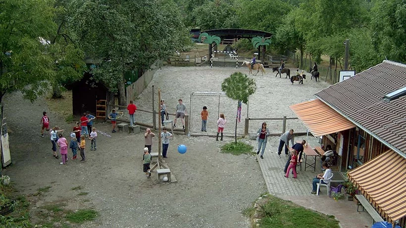 Jugendfarm Stuttgart-Stammheim - Das Bild zeigt eine Luftaufnahme des Hofes mit spielenden Kindern und Ponys im Hintergrund.