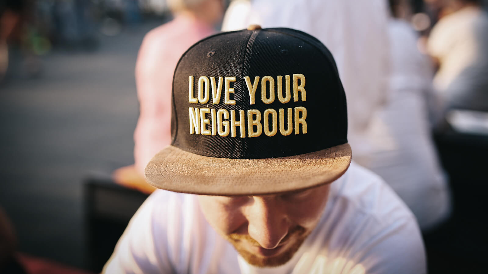 Mann mit Cap mit Aufschrift „Love your neighbour“ als Symbol für Nächstenliebe, Solidarität und soziale Verantwortung.